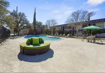 A round green and white hot tub sits in the middle of a concrete courtyard.